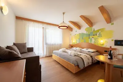 a bedroom with a bed and a couch at Hotel Dolomites Inn in Canazei