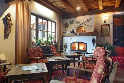 a living room with a fireplace and tables and chairs at Hotel Dolomites Inn in Canazei
