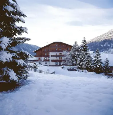 a building covered in snow in front of a river at Hotel Ciampian in Moena