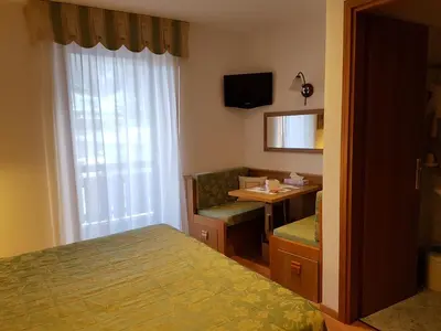 a bedroom with a bed and a desk and a mirror at Hotel Ciampian in Moena