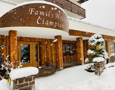 a snow covered building with a sign that reads farmers shop champion at Hotel Ciampian in Moena