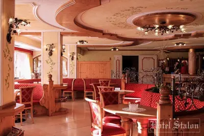 a dining room with a ceiling with a chandelier at Hotel Stalon Alpine Chic in San Martino di Castrozza