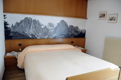 a bedroom with a bed with a mountain mural on the wall at Hotel Garni Soreie in Pozza di Fassa