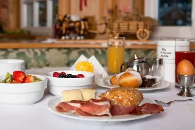 a table topped with plates of food and breakfast foods at Hotel Garni Soreie in Pozza di Fassa