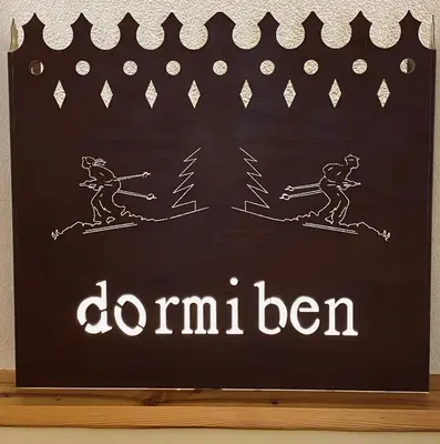 a chalkboard sign with two people on skis at Hotel Laurino in Pozza di Fassa