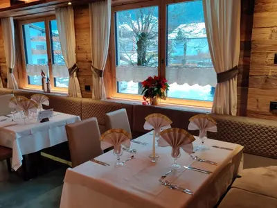 a dining room with two tables and windows at Hotel Laurino in Pozza di Fassa