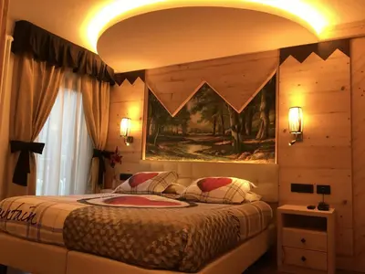 a bedroom with a bed with a painting on the wall at Hotel Laurino in Pozza di Fassa