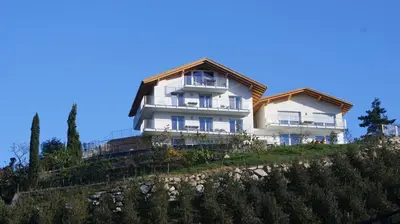 a large white building on a hill with trees at Residence Fiegl in Schenna
