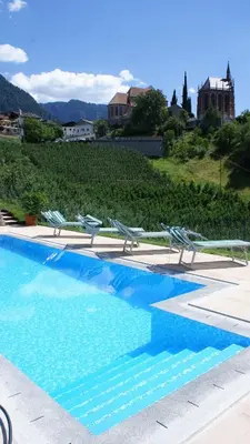 a swimming pool with lounge chairs at Residence Fiegl in Schenna