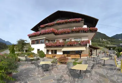 a building with tables and chairs in front of it at Pension Obertaberhof in Schenna