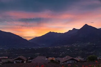 a sunset in the mountains with houses and mountains at Pension Obertaberhof in Schenna