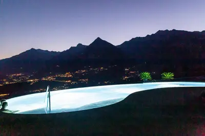 a large swimming pool with mountains in the background at Pension Obertaberhof in Schenna