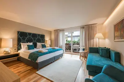 a bedroom with a king sized bed and a couch at Hotel Mignon Meran Park & Spa in Merano