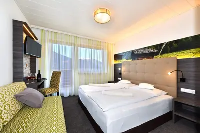 a bedroom with a large white bed and a desk at Hotel Tyrol Plose in Bressanone