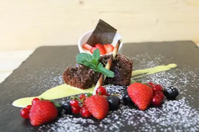 a chocolate dessert with fruit on a black plate at Hotel Tyrol Plose in Bressanone