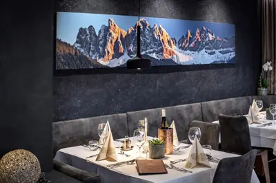 a dining room with a table with white tablecloths and wine glasses at Hotel Tyrol Plose in Bressanone