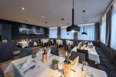 a restaurant with white tables and chairs and windows at Hotel Tyrol Plose in Bressanone