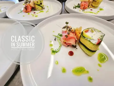a table with white plates with food on them at Hotel Tyrol Plose in Bressanone