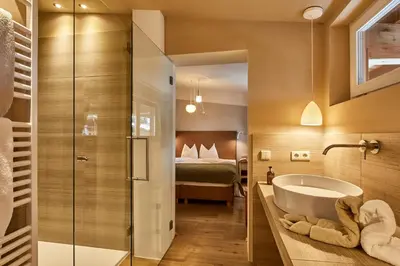 a bathroom with a tub and a bedroom with a bed at Appartamenti La Sajun & Les Viles in La Villa