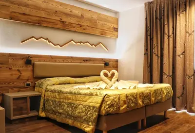 a bedroom with a bed with a wooden wall at Hotel Panorama Wellness & Resort in Malosco