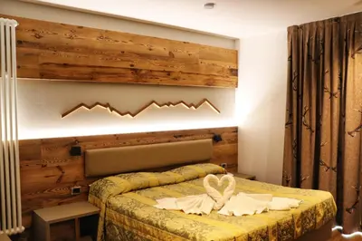 a bedroom with a bed with a wooden wall at Hotel Panorama Wellness & Resort in Malosco