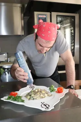 a man in a kitchen preparing a plate of food at Hotel Panorama Wellness & Resort in Malosco