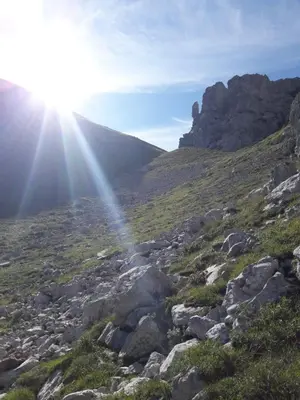 a sun shining on a hill with rocks and grass at B&B DOLOMIA in Sagron Mis