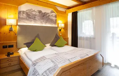 a bedroom with a large bed with green pillows at Hotel Cirelle Suite & Spa in Canazei