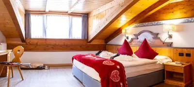 a bedroom with a large bed with red pillows at Hotel Cirelle Suite & Spa in Canazei