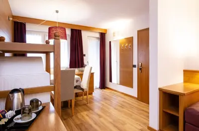 a small apartment with a bunk bed and a dining room at Hotel Cirelle Suite & Spa in Canazei