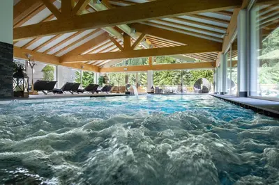a swimming pool in a house with a wooden ceiling at Hotel Cirelle Suite & Spa in Canazei