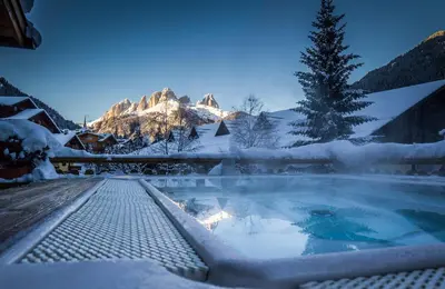 a hot tub covered in snow in front of a mountain at Residence Cirelle Suite & Spa in Canazei