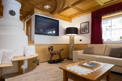 a living room with a couch and a tv on the wall at Residence Cirelle Suite & Spa in Canazei