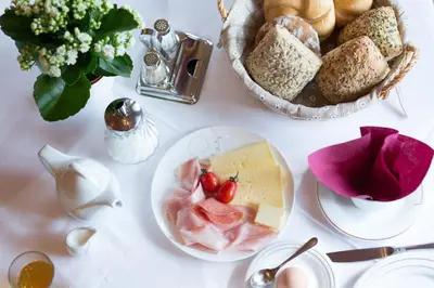 a white table with a plate of food and bread at LINGHOF in Tirolo