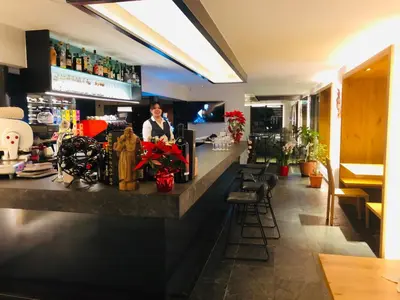 a woman standing at a bar in a restaurant at Hotel Silvana in Selva di Val Gardena