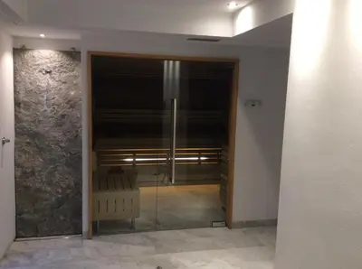 a glass door leading into a room with a chair at Hotel Silvana in Selva di Val Gardena