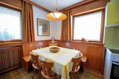 a dining room with a table and some windows at Apartments Cesa Bruma in Ortisei