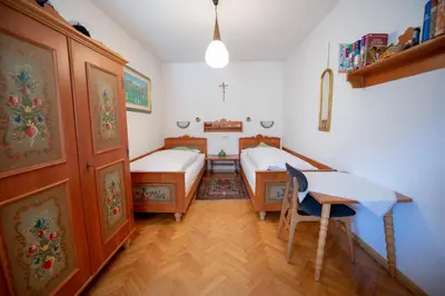 a bedroom with two beds and a desk and a table at Apartments Cesa Bruma in Ortisei