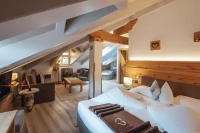 a bedroom with a large bed and a living room at Bio Boutique Hotel Laurino in Cavalese