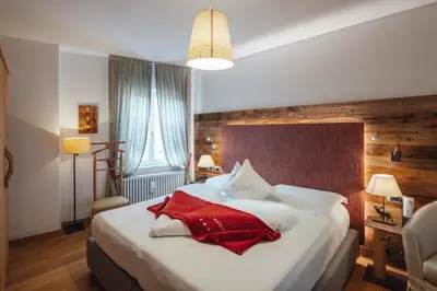 a bedroom with a bed with a red blanket on it at Bio Boutique Hotel Laurino in Cavalese