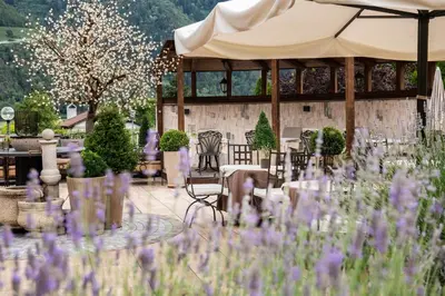 a garden with purple flowers in front of a pavilion at Hotel Rössl in Rablà