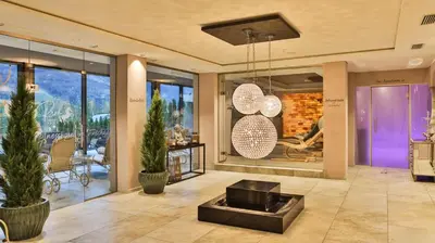 a lobby with a fireplace and a table and chairs at Hotel Rössl in Rablà