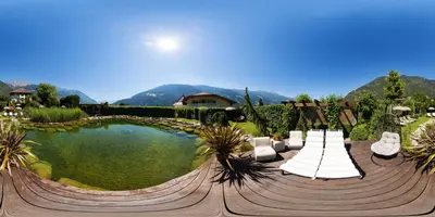 a swimming pool with chairs and a table and a house at Hotel Rössl in Rablà