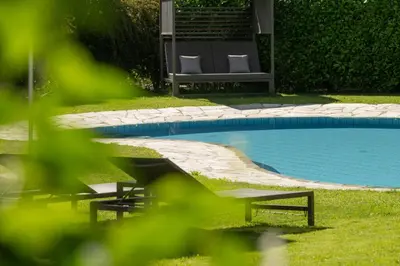 a swimming pool with two lounge chairs next to it at Pension Sandhofer in Nalles