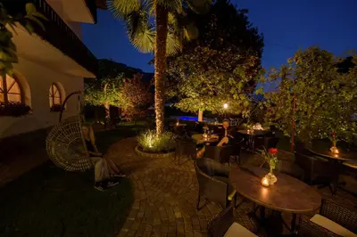a woman sitting at a table in a restaurant at night at Pension Sandhofer in Nalles