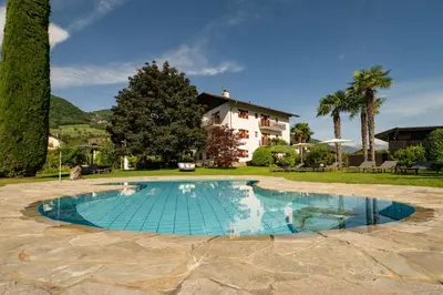 a swimming pool with a house in the background at Pension Sandhofer in Nalles