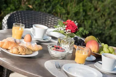 a table with a breakfast of croissants and fruit and juice at Pension Sandhofer in Nalles