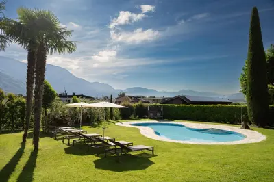 a resort with a pool and chairs and a palm tree at Pension Sandhofer in Nalles