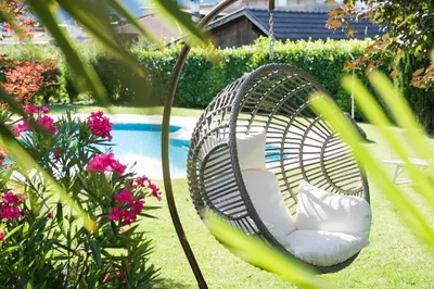 a wicker chair sitting in a yard next to a pool at Pension Sandhofer in Nalles