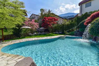 a swimming pool with a waterfall in a yard at Hotel Zum Mohren in Tesimo
